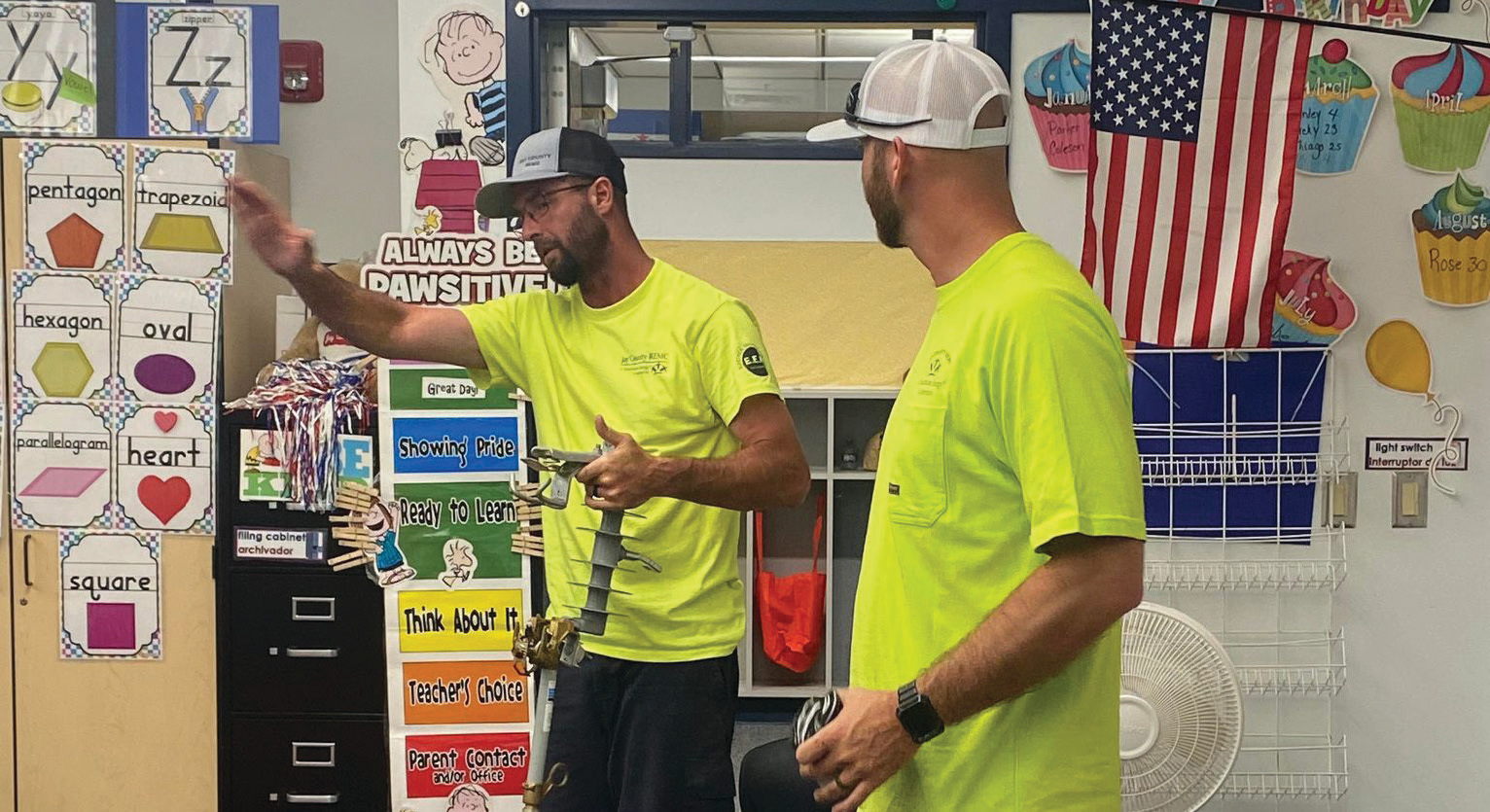 Jay County REMC linemen Dan Paxson, left, and Mason Bechdolt teach students about electrical safety.