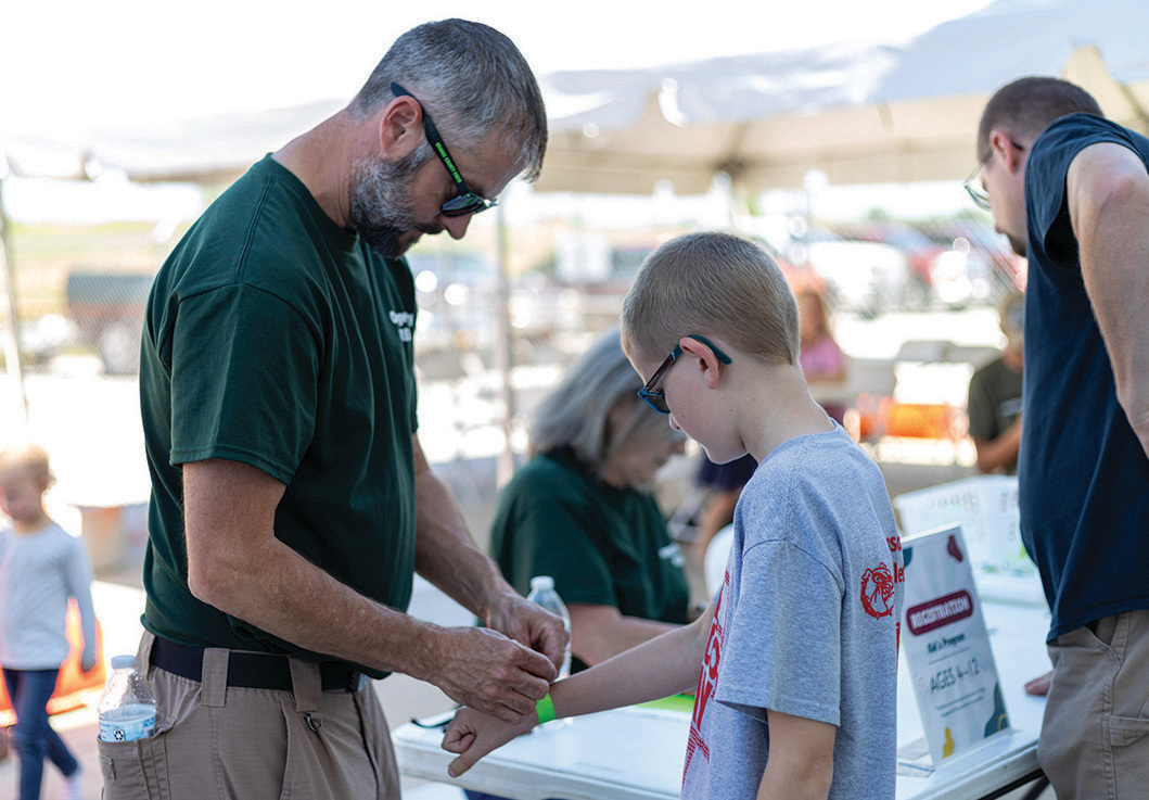 REMC Fiber’s Charlie Rollins applies a wristband to a young member entering the kids’ activity area.