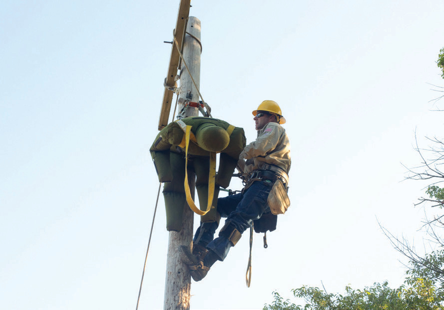 Lead Lineman Shane Henderson safely secures the mannequin during pole top rescue training.