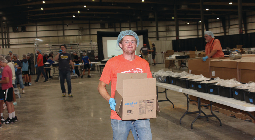 LaGrange County REMC’s Owen Bowersox carries a box filled with MannaPack Rice to be weighed and sealed.